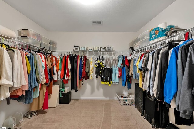 walk in closet with light carpet