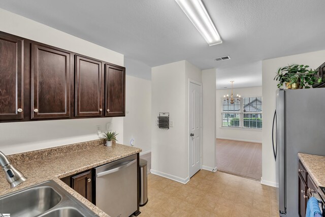 kitchen featuring dark brown cabinets, a chandelier, sink, hanging light fixtures, and stainless steel appliances