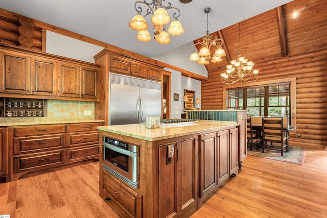 kitchen with appliances with stainless steel finishes, hanging light fixtures, log walls, and a notable chandelier