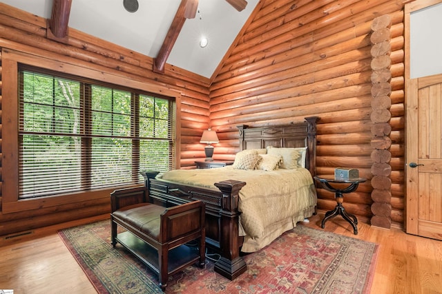 bedroom featuring light hardwood / wood-style floors, beam ceiling, ceiling fan, and rustic walls