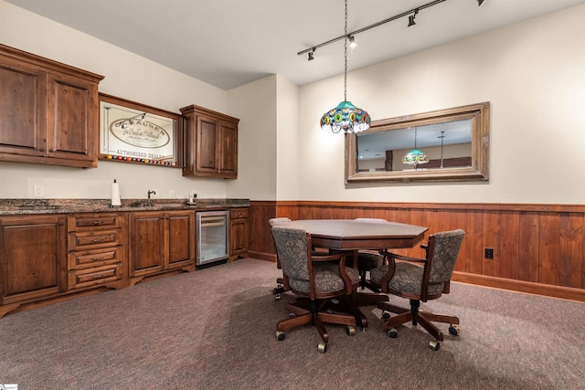 carpeted dining room with indoor wet bar, wood walls, wine cooler, and track lighting