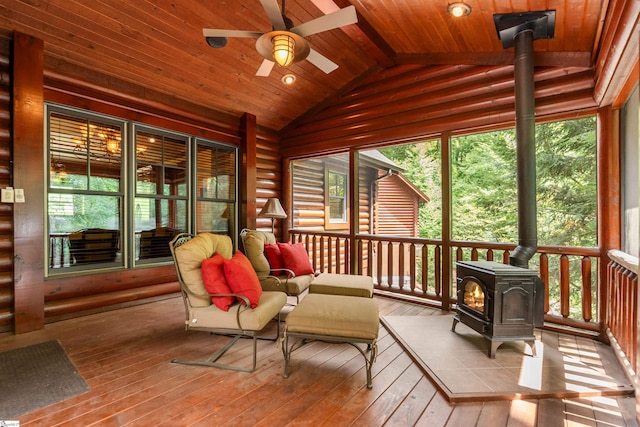 sunroom featuring a wood stove, lofted ceiling, ceiling fan, and wooden ceiling