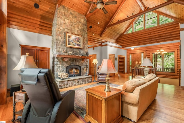 living room featuring ceiling fan with notable chandelier, a stone fireplace, wood ceiling, and high vaulted ceiling