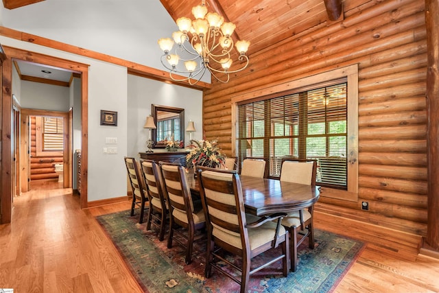 dining room with wood ceiling, rustic walls, high vaulted ceiling, an inviting chandelier, and light hardwood / wood-style floors