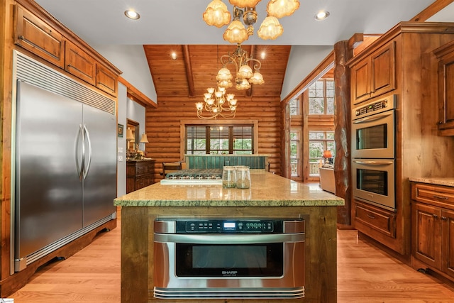 kitchen with hanging light fixtures, a kitchen island, stainless steel appliances, lofted ceiling, and an inviting chandelier