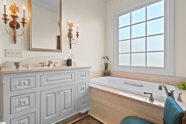 bathroom with ornamental molding, tiled tub, and vanity