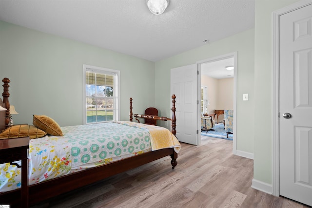 bedroom featuring a textured ceiling and light hardwood / wood-style flooring