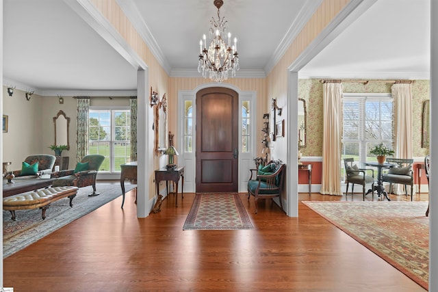 foyer entrance featuring hardwood / wood-style flooring, crown molding, and a chandelier