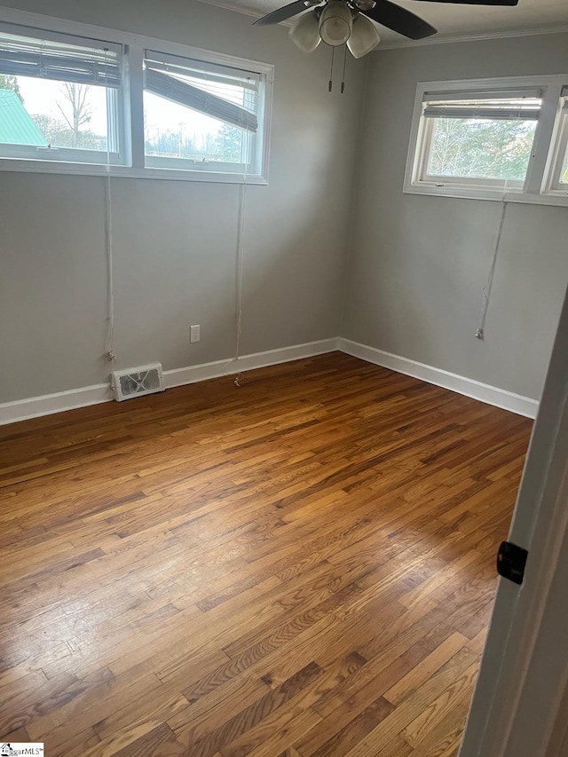 unfurnished room with ceiling fan, hardwood / wood-style flooring, ornamental molding, and a wealth of natural light