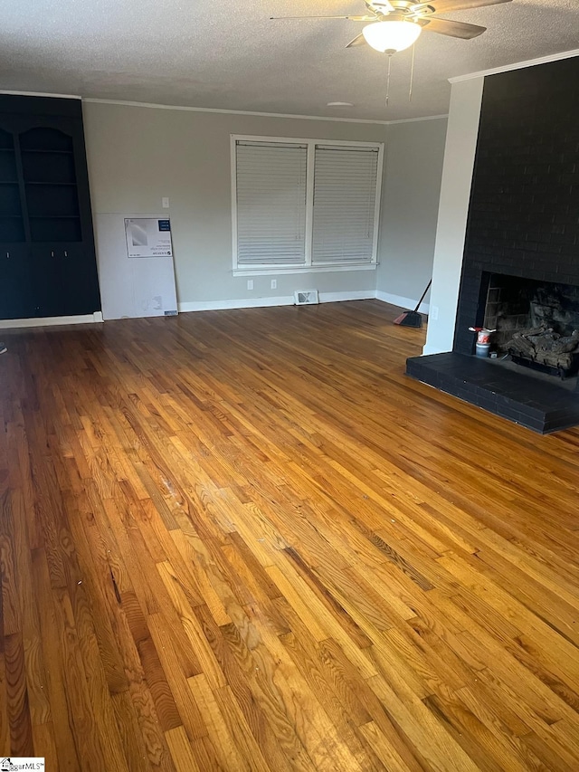 unfurnished living room featuring a textured ceiling, hardwood / wood-style flooring, a large fireplace, and ceiling fan