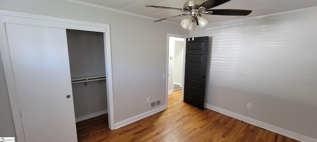 unfurnished bedroom with hardwood / wood-style floors, crown molding, a closet, and ceiling fan