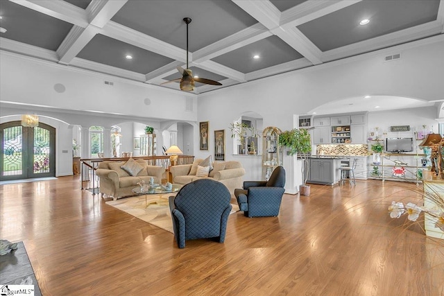 living room featuring light wood-type flooring, coffered ceiling, beam ceiling, and ceiling fan