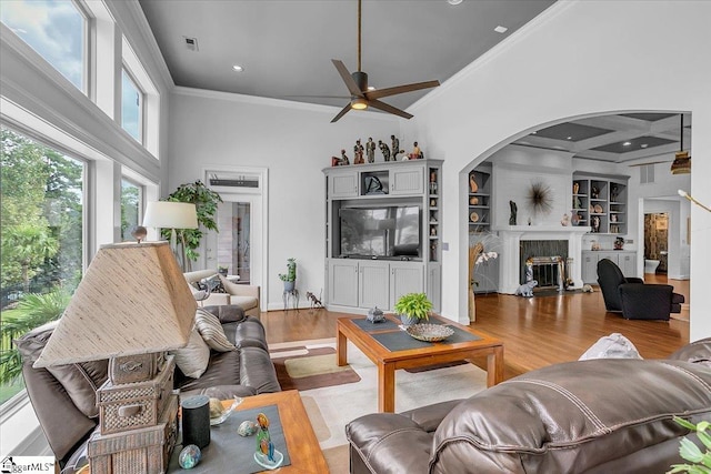 living room with a towering ceiling, ornamental molding, ceiling fan, and light hardwood / wood-style flooring