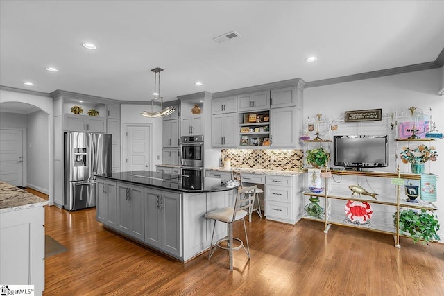 kitchen with gray cabinets, hardwood / wood-style floors, pendant lighting, and stainless steel appliances