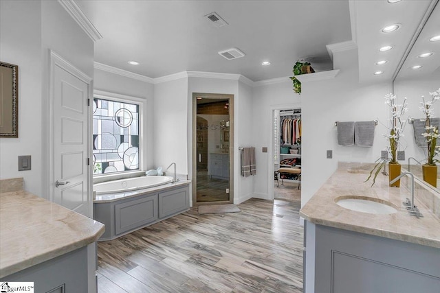 bathroom featuring plus walk in shower, vanity, ornamental molding, and hardwood / wood-style floors