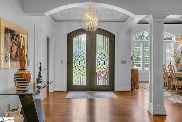 entryway featuring ornamental molding, wood-type flooring, french doors, an inviting chandelier, and ornate columns