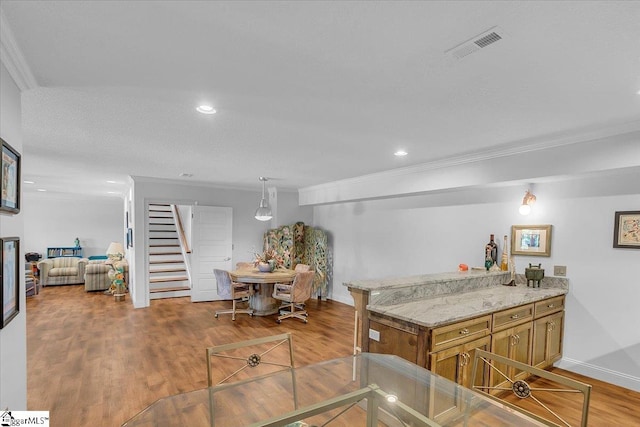 kitchen with ornamental molding, light wood-type flooring, kitchen peninsula, and hanging light fixtures