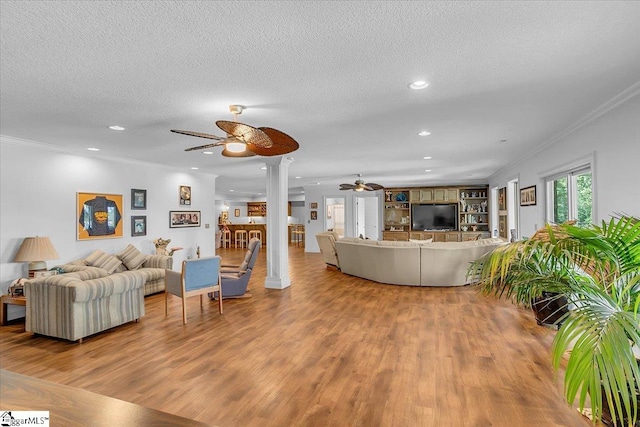 living room with ceiling fan, hardwood / wood-style flooring, ornamental molding, and a textured ceiling