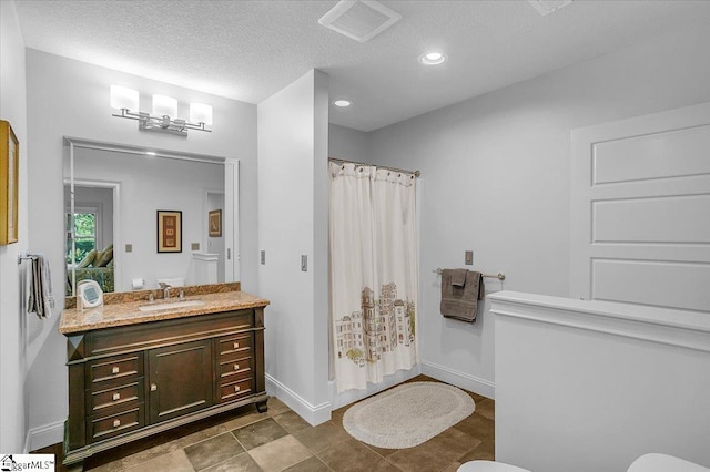 bathroom with a textured ceiling, vanity, and toilet