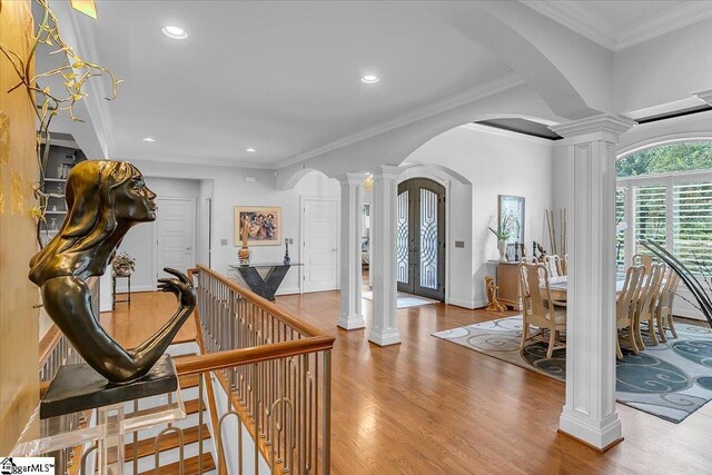 entryway featuring light hardwood / wood-style floors, ornamental molding, and ornate columns