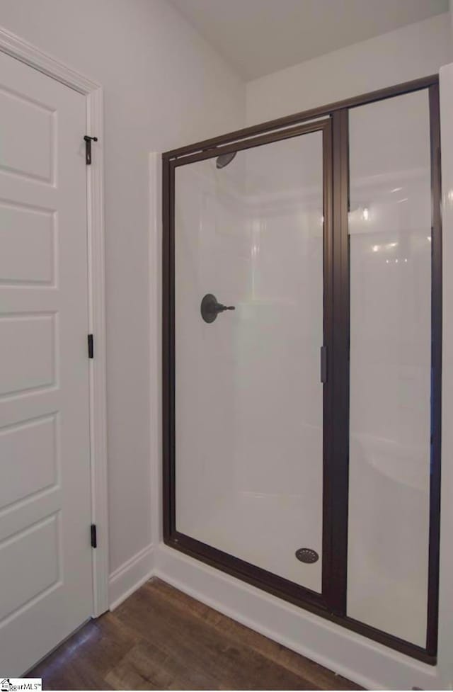 bathroom with a shower with door and hardwood / wood-style flooring