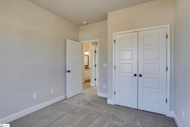 unfurnished bedroom with a closet and light colored carpet