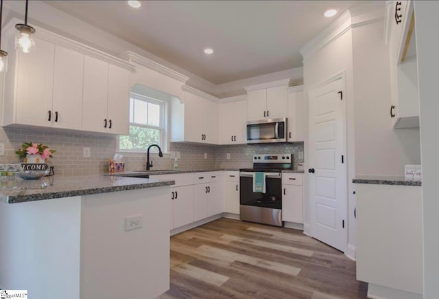 kitchen with pendant lighting, sink, white cabinets, light hardwood / wood-style flooring, and appliances with stainless steel finishes