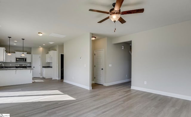 unfurnished living room featuring light wood-type flooring, ceiling fan, and sink