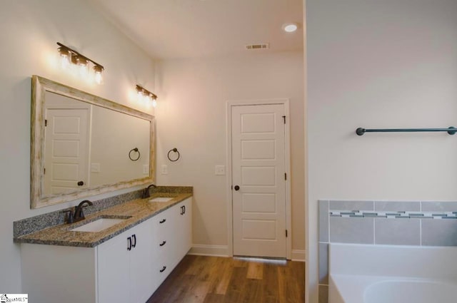 bathroom featuring wood-type flooring, vanity, and a bathing tub