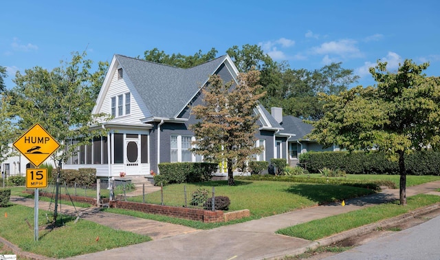 view of front of home with a sunroom and a front lawn