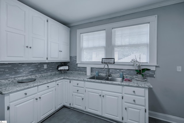 kitchen featuring light stone counters, tasteful backsplash, sink, white cabinetry, and crown molding