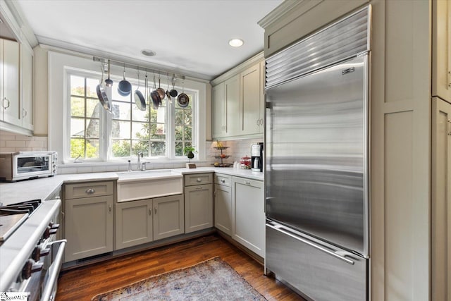 kitchen featuring high quality appliances, dark wood-type flooring, decorative backsplash, and gray cabinetry