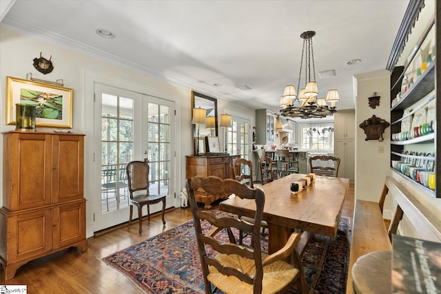 dining room featuring wood-type flooring, a notable chandelier, french doors, and ornamental molding