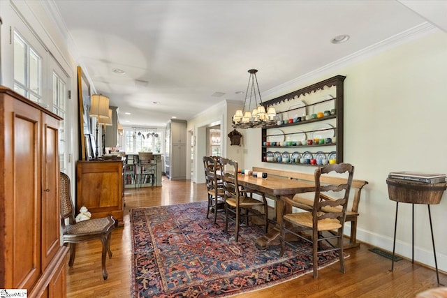 dining room with hardwood / wood-style flooring, crown molding, and a chandelier