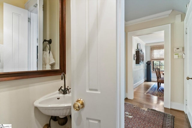 bathroom with hardwood / wood-style flooring, crown molding, and sink