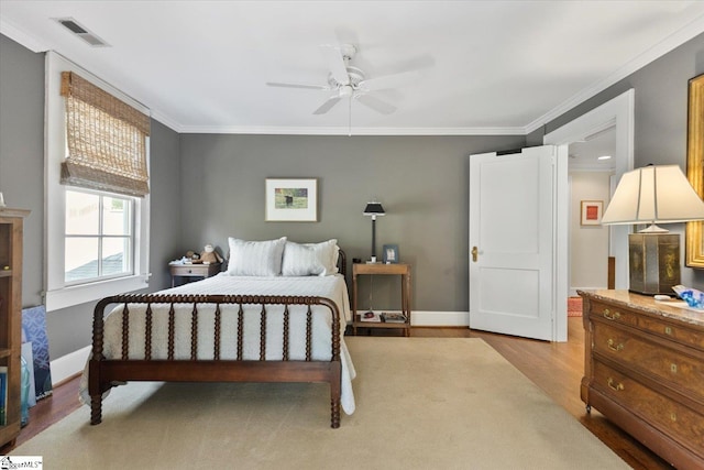 bedroom with ceiling fan, ornamental molding, and light hardwood / wood-style floors