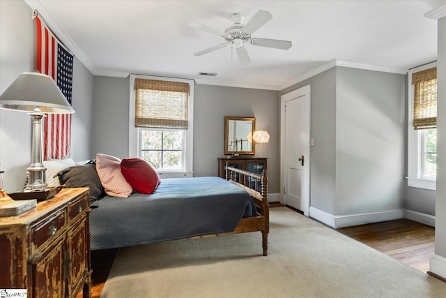 bedroom with ornamental molding, wood-type flooring, multiple windows, and ceiling fan