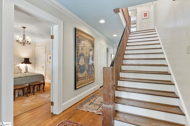 stairway with ornamental molding, a chandelier, and hardwood / wood-style floors