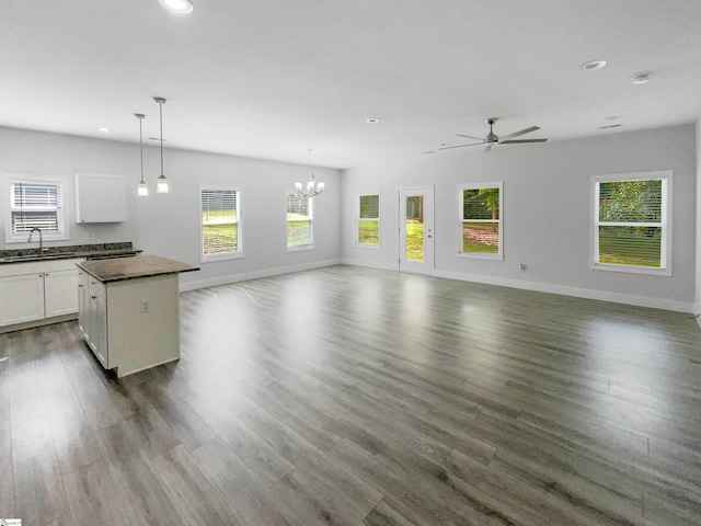 unfurnished living room with sink, ceiling fan with notable chandelier, and dark hardwood / wood-style flooring