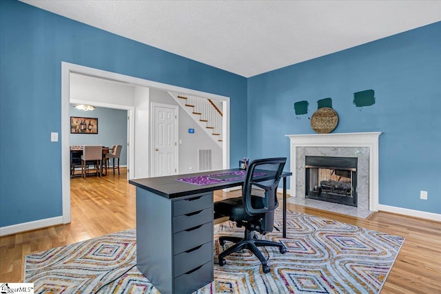 office area featuring a high end fireplace, a textured ceiling, and hardwood / wood-style flooring