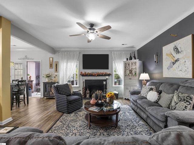 living room featuring ceiling fan, ornamental molding, beamed ceiling, and hardwood / wood-style floors