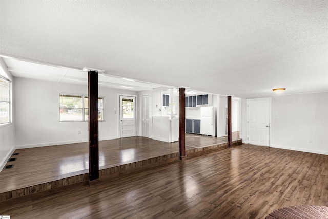 unfurnished living room with a textured ceiling, dark hardwood / wood-style flooring, and ornate columns