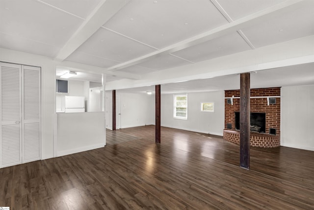 basement with a brick fireplace, white fridge, and dark hardwood / wood-style flooring