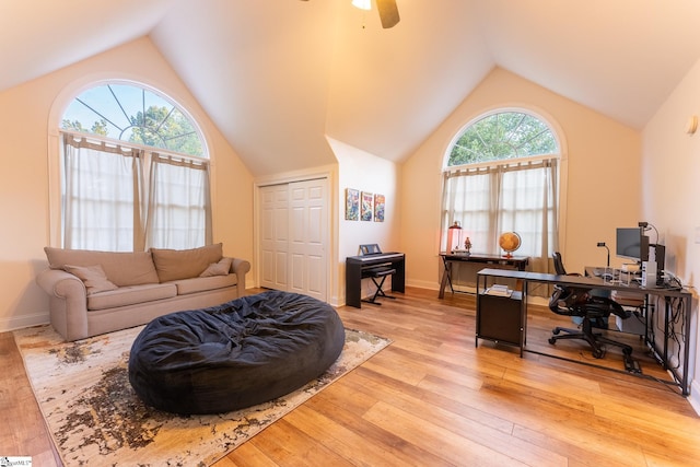 living room featuring ceiling fan, light hardwood / wood-style flooring, vaulted ceiling, and a wealth of natural light