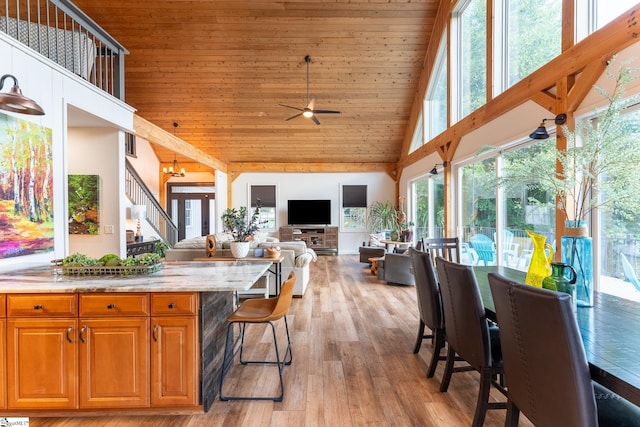 kitchen with ceiling fan, light stone counters, wood ceiling, light hardwood / wood-style flooring, and high vaulted ceiling