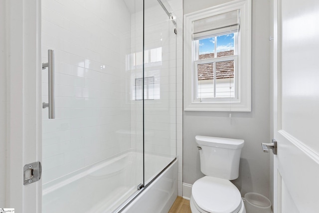 bathroom with enclosed tub / shower combo and toilet