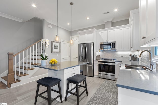 kitchen featuring sink, a kitchen island, white cabinetry, appliances with stainless steel finishes, and light hardwood / wood-style floors