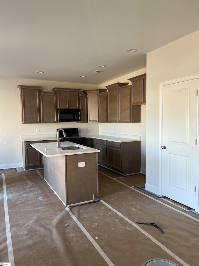 kitchen with dark brown cabinets, sink, a kitchen island with sink, and black appliances