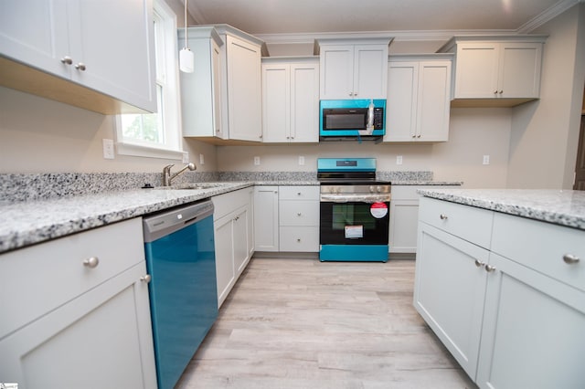 kitchen with appliances with stainless steel finishes, ornamental molding, light wood finished floors, a sink, and light stone countertops
