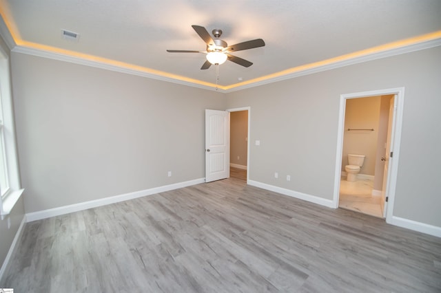 unfurnished bedroom with crown molding, wood finished floors, baseboards, ensuite bath, and ceiling fan